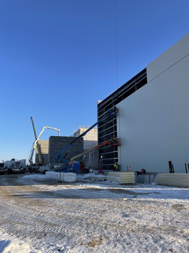 Crew on boom lifts installing tall insulated metal wall panels