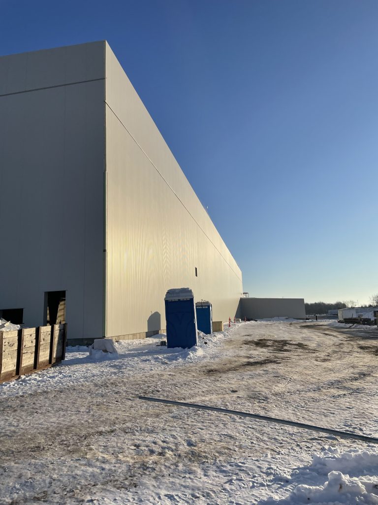 Tall wall of insulated metal panels on a large steel building, with snow on the ground