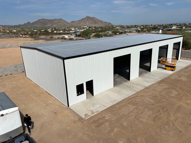 Aerial view of a white multi-bay steel building below a rocky mountain