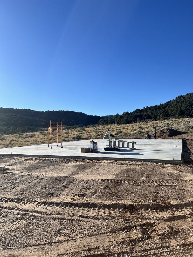 Concrete slab with anchor bolts, a level on a tripod and rolling scaffolding in Glade Park, Colorado
