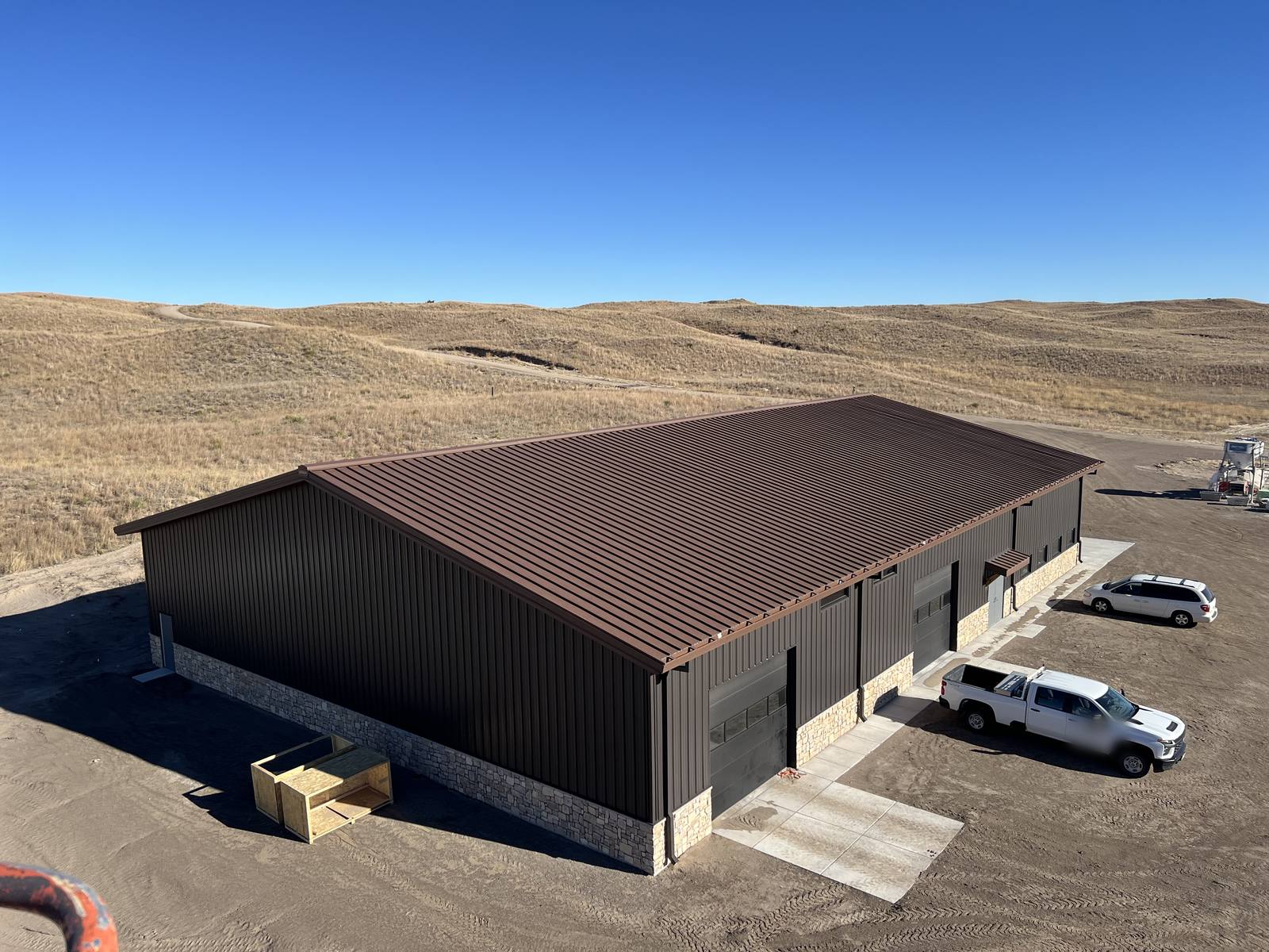 Dark steel building with a brown metal roof and stone wainscot in the Nebraska Sandhills near Mullen