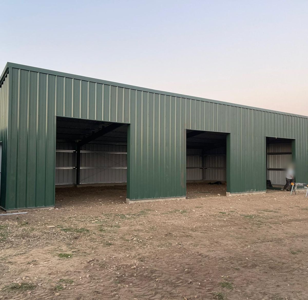Green steel equipment shed with three open bays near Longmont, Colorado