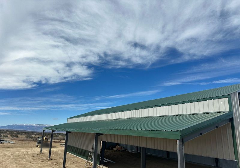 Green metal roofs of a steel barn and its long lean-to, seen from a lift, near Hotchkiss, Colorado