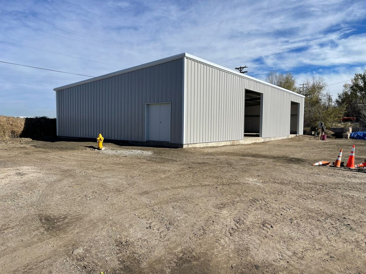 White steel building with a double walk door and two open bays in Littleton, Colorado